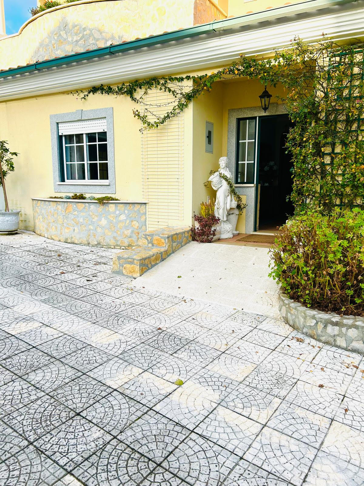 Front porch and entrance from the driveway showing the tiled approach to the open front door