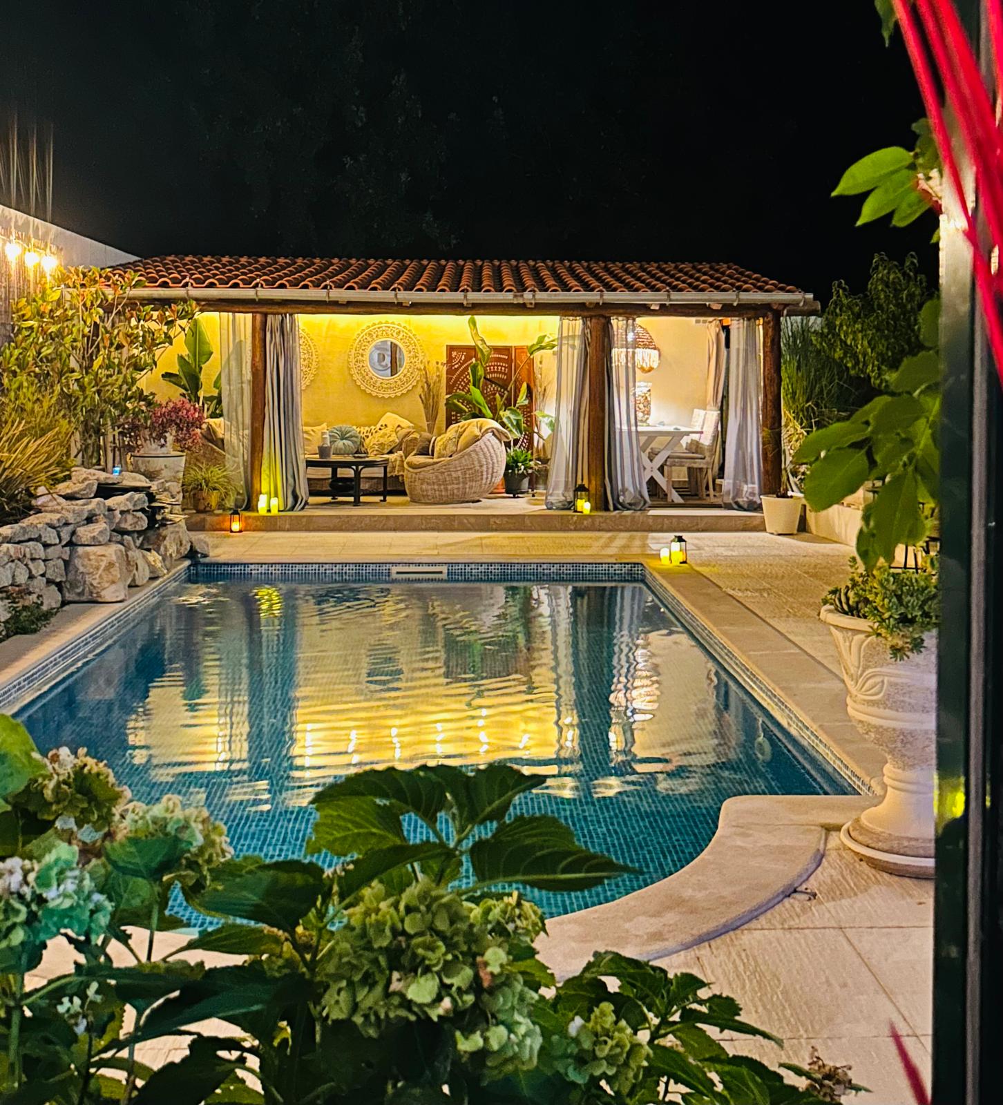 Cabana lit up at night reflected in the pool