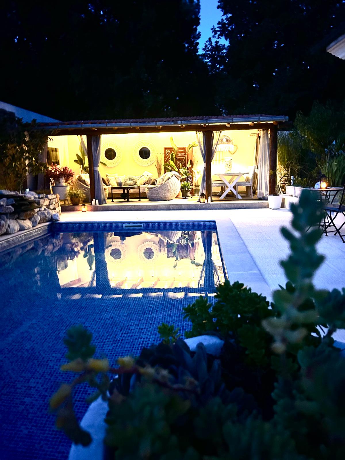 Turquoise-lit pool at night with cabana glowing behind